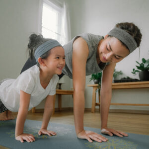 Mom and daughter doing yoga at home in December